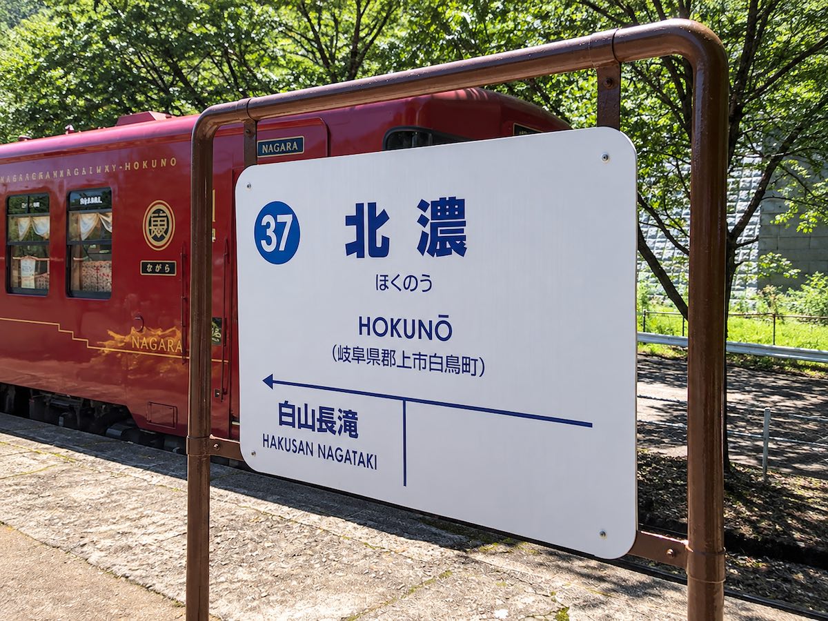 長良川鉄道の終着駅・北濃駅の駅名標と、停車中の赤い観光列車『ながら』