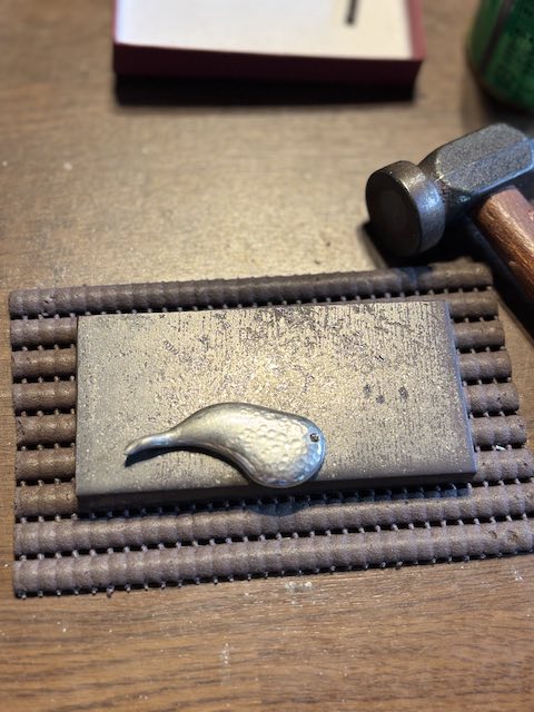 金槌の丸い面で錫を叩くアクセサリー制作工程