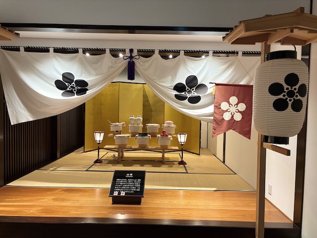 高岡御車山会館に展示された山宿の再現と梅鉢紋が並ぶ幔幕