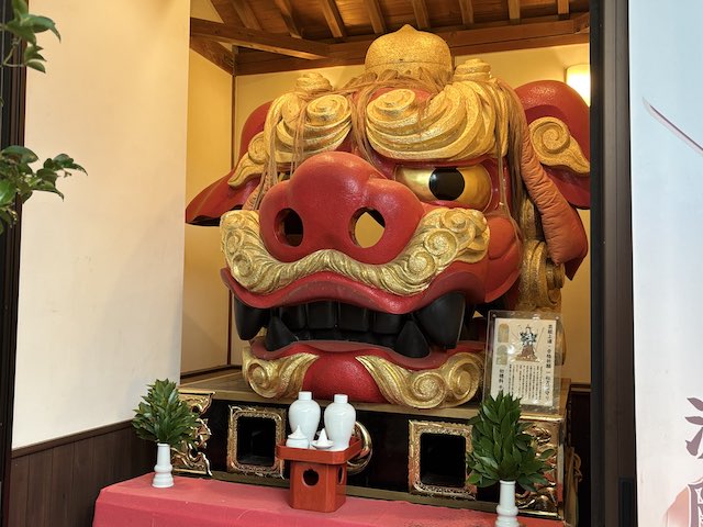 赤い顔と金色の巻き毛を持つ波除神社のお歯黒獅子の全体像