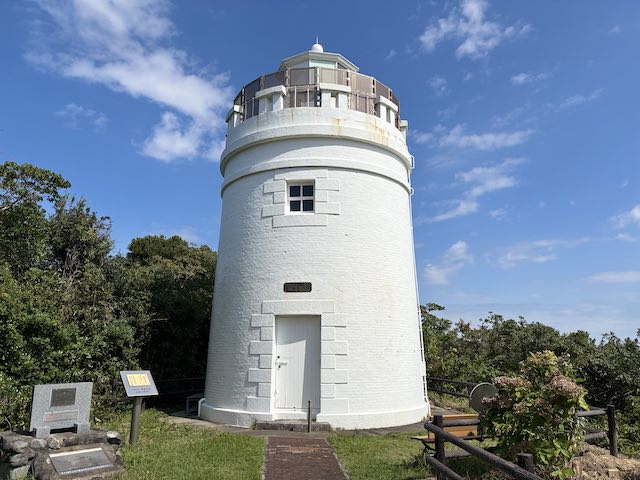 近くから見た菅島灯台の白い円筒形の塔と上部の回廊