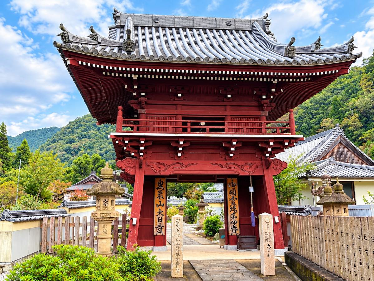 四国八十八ヶ所第四番札所・大日寺の朱色の鐘楼門と背後の山々